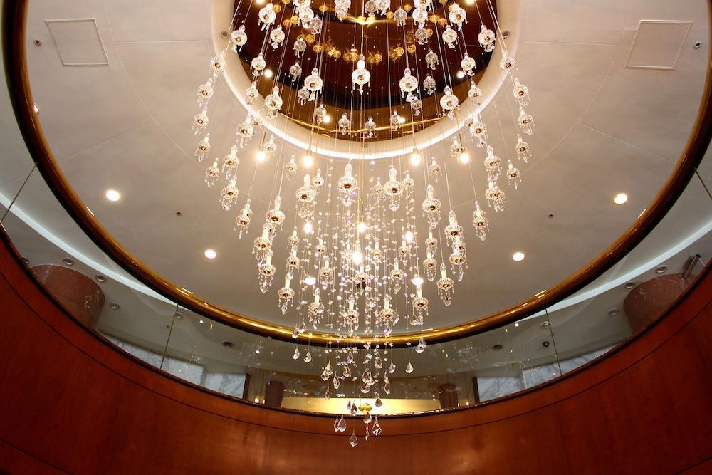 فندق إيفرجرين لوريل، تايتشونج تايتشونغ المظهر الخارجي الصورة The photo shows an elegant chandelier hanging from a ceiling. The chandelier features numerous hanging crystals that reflect light, creating a sparkling effect. The ceiling itself is circular and designed with a smooth surface, accented by a circular