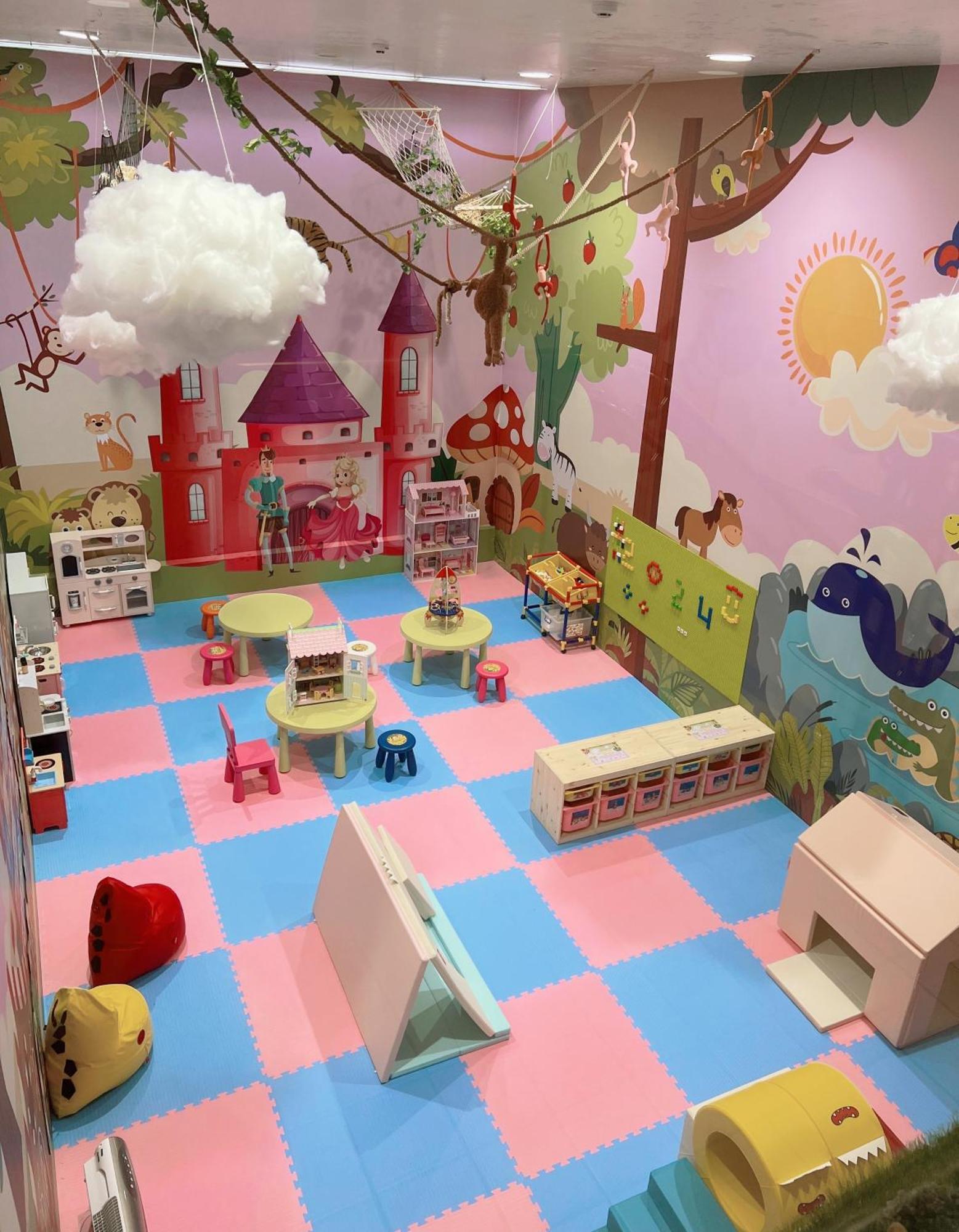 فندق إيفرجرين لوريل، تايتشونج تايتشونغ المظهر الخارجي الصورة The photo shows a colorful playroom designed for children. It features a vibrant mural with a fairytale castle, trees, and playful animals on the walls. The floor is covered with interlocking foam tiles in pink and blue, providing a soft play surface
