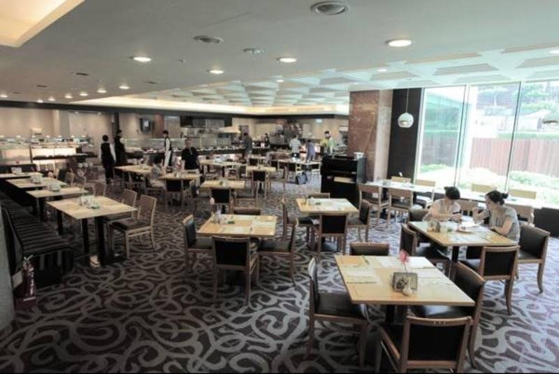 فندق إيفرجرين لوريل، تايتشونج تايتشونغ المظهر الخارجي الصورة The photo shows a spacious restaurant or dining area with a modern interior design. There are several tables arranged throughout the room, some of which are set for dining while others appear to be empty. The decor includes a patterned carpet and lar