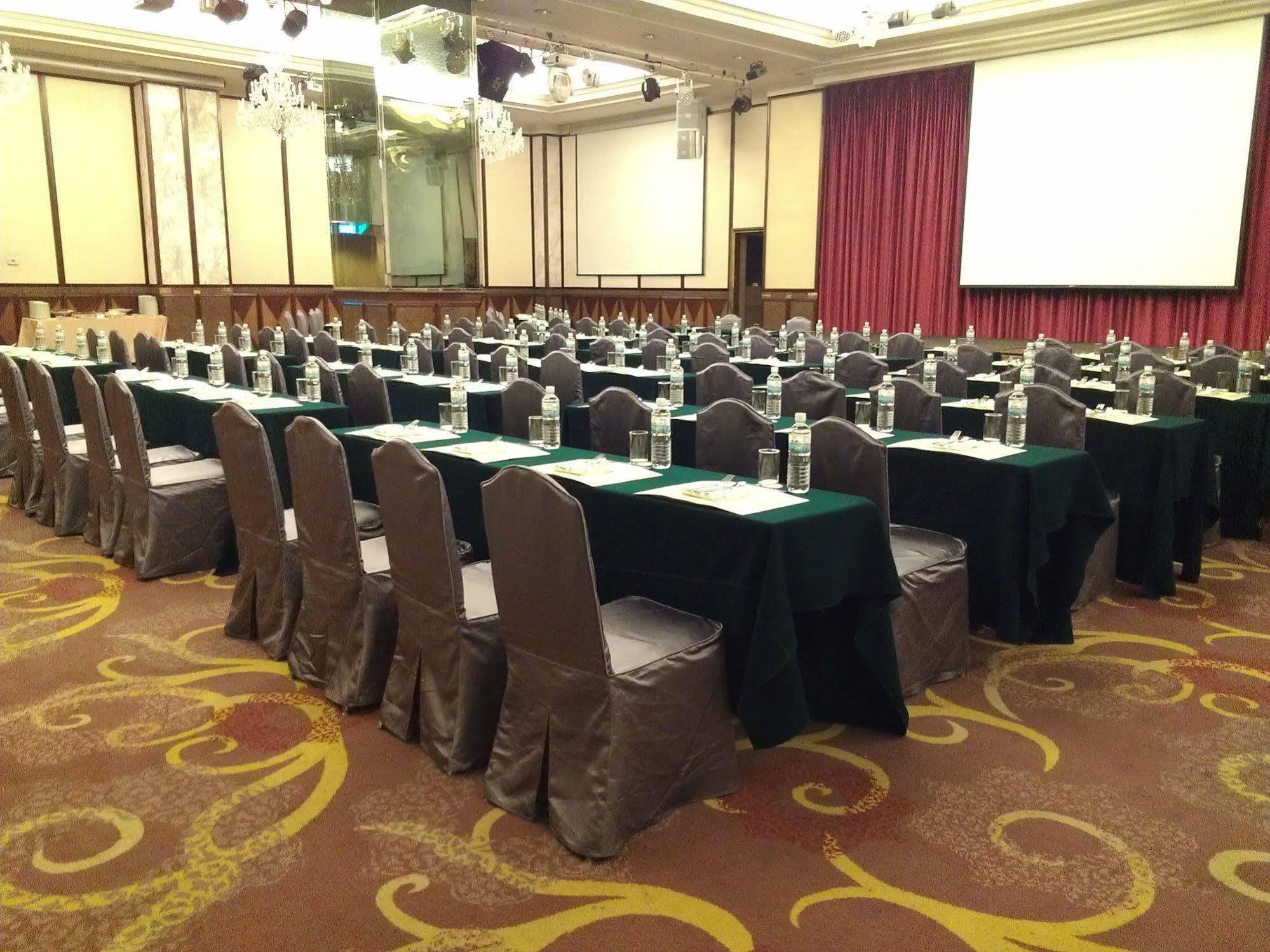 فندق إيفرجرين لوريل، تايتشونج تايتشونغ المظهر الخارجي الصورة The photo shows a large conference or meeting room set up with multiple tables arranged in a structured manner. Each table is covered with a tablecloth, alternating between black and green. There are chairs around each table, and each place setting a