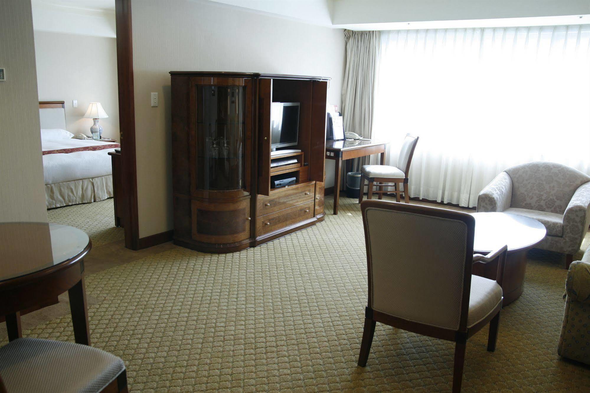 فندق إيفرجرين لوريل، تايتشونج تايتشونغ المظهر الخارجي الصورة The photo shows an interior of a hotel room suite. The space includes a living area with several pieces of furniture. There is a coffee table and chairs, creating a comfortable seating area. A wooden cabinet with a TV inside is situated against one w
