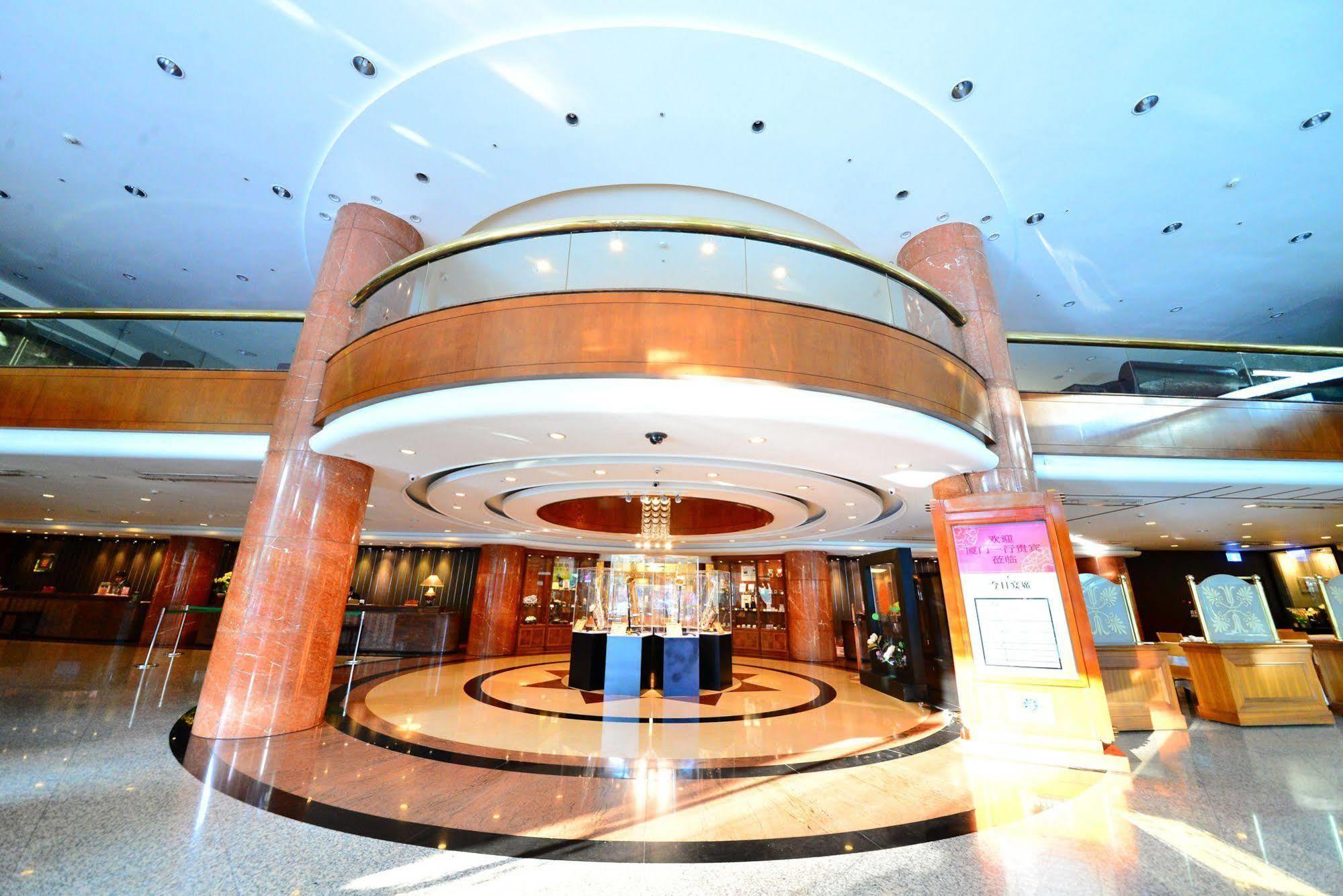 فندق إيفرجرين لوريل، تايتشونج تايتشونغ المظهر الخارجي الصورة The photo shows the interior of a spacious lobby area. It features a modern architectural design with polished surfaces and a circular ceiling structure. The walls are accented with wooden panels, and there is a central chandelier hanging from the ce