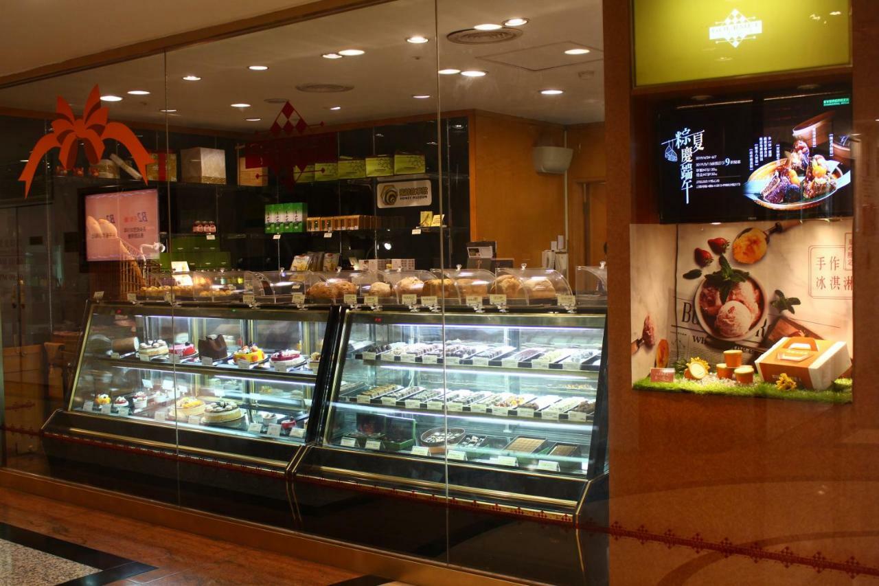 فندق إيفرجرين لوريل، تايتشونج تايتشونغ المظهر الخارجي الصورة The photo shows a display case in a bakery or dessert shop. The glass case is filled with a variety of pastries, cakes, and desserts arranged neatly. Behind the display, there is a counter with additional items and desserts visible. The walls are dec