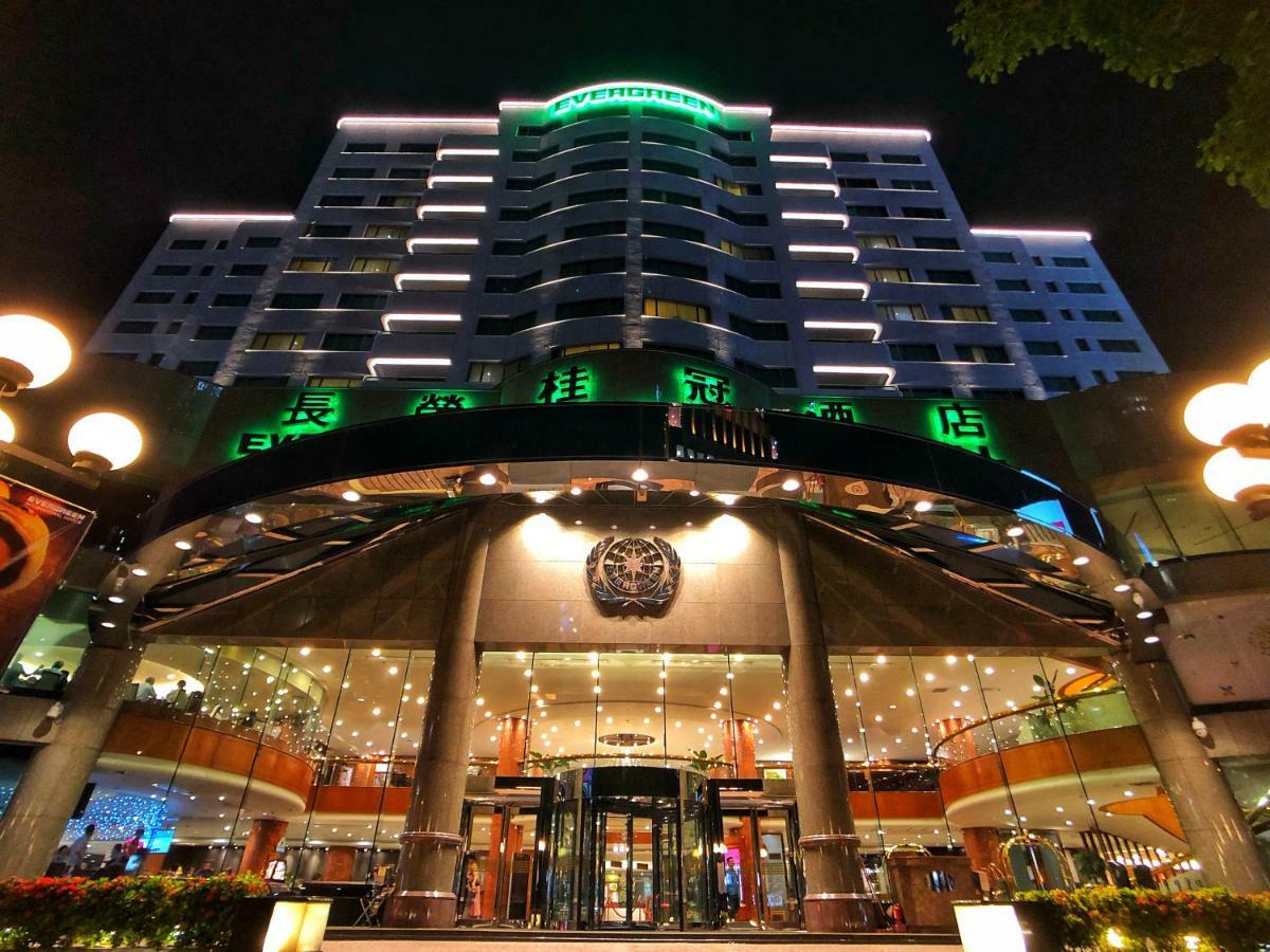 فندق إيفرجرين لوريل، تايتشونج تايتشونغ المظهر الخارجي الصورة The photo shows a modern building at night, featuring a grand entrance with illuminated signage. The structure has multiple stories with a sleek design, adorned with green lighting that highlights its architectural features. The entrance is spacious 