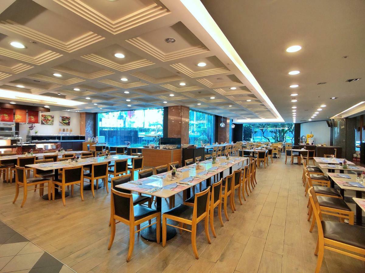 فندق إيفرجرين لوريل، تايتشونج تايتشونغ المظهر الخارجي الصورة The photo shows the interior of a restaurant. It features a spacious dining area with several wooden tables and chairs arranged in rows. The floor has a light wood finish, complementing the stylish design. The ceiling is decorated with a modern patte