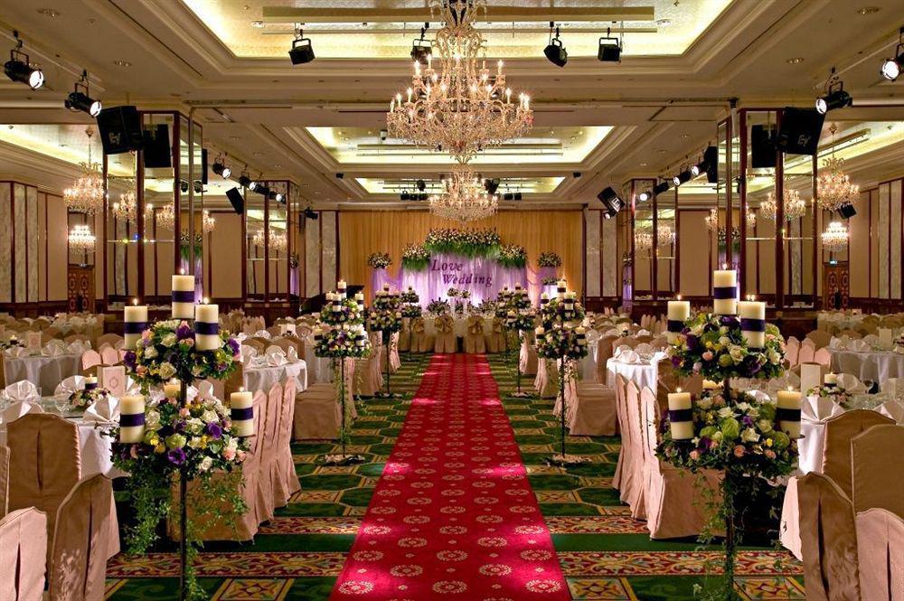 فندق إيفرجرين لوريل، تايتشونج تايتشونغ المظهر الخارجي الصورة The photo shows an elegantly decorated banquet hall set up for a wedding or formal event. The center aisle is lined with rows of elegantly draped chairs and features a bright red carpet. On either side of the aisle, there are beautifully arranged flo