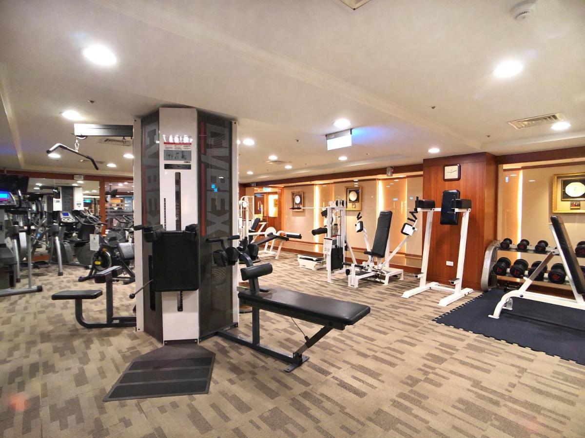 فندق إيفرجرين لوريل، تايتشونج تايتشونغ المظهر الخارجي الصورة The photo shows an indoor gym or fitness area. It features various workout equipment, including:

- A multi-station gym machine in the center for strength training.
- Weight benches and free weights organized on shelves.
- Cardio equipment, likely tr