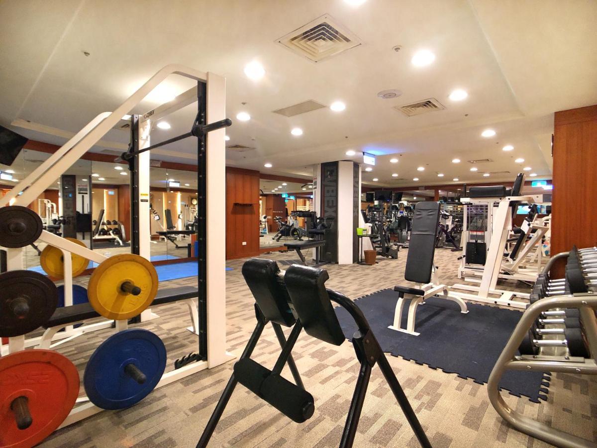 فندق إيفرجرين لوريل، تايتشونج تايتشونغ المظهر الخارجي الصورة The photo shows a gym interior with various workout equipment. On the left, there are weights of different colors stacked on a weight rack. In the foreground, there's a bench for exercises, and in the background, multiple machines for strength traini
